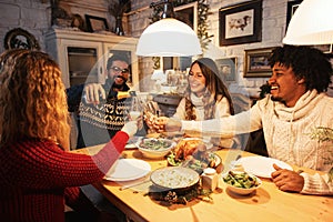 Group of people praying before a mealGroup of friends eating dinner together, cheering with champagne