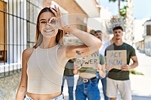 Group of people protesting and giving slogans at the street smiling happy doing ok sign with hand on eye looking through fingers