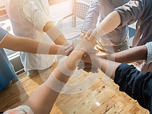 Group of people putting their hands working together on wooden background in office. group support teamwork cooperation concept.