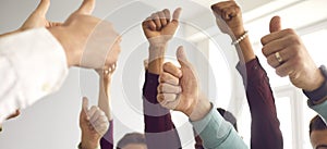 Group of people raising hands and giving thumbs-up, celebrating success and teamwork