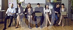 Group of people reading or using laptop computers while waiting for business meeting