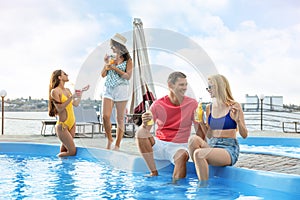 Group of people with refreshing drinks enjoying fun pool party