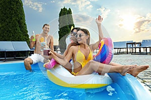 Group of people with refreshing drinks enjoying fun pool party