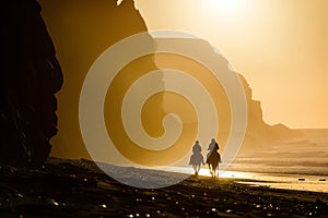 Group of people riding horses in beautiful Irish landscape on dramatic sunset. Tourists admiring scenic view while on horseback