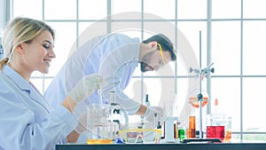 Group of people scientist holding a tube with liquid substance. Man and woman Research is working in the Laboratory with