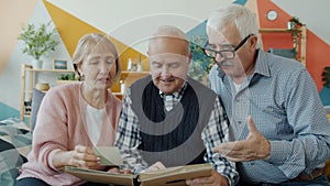 Group of people senior men and woman watching pictures in album talking having fun
