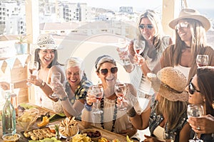 Group of people or seven women together having fun and enjoying - friendship of ladys with glass of wine - wooden table full of