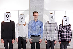 A group of people with sheets with question marks on their faces except a guy with a smile