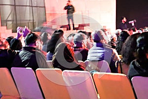 Group of people sitting on the chairs and watching stage performance live