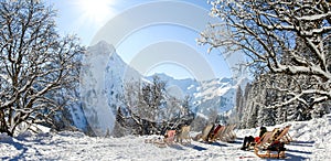Group of people sitting with deck chairs in winter mountains. Sunbathing in snow. Germany, Bavaria, Allgau photo