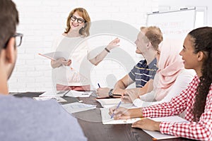 Group of people sitting at the desk and looking at the speaker