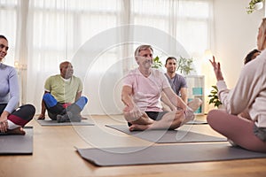 Group Of People Sitting On Exercise Mats Meeting For Fitness Or Yoga Class In Community Center