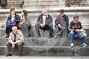 Group people sitting on marble steps, Catania, Sicily. Italy