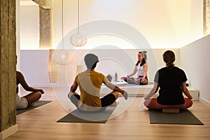 A group of people are sitting on yoga mats meditating in a room.