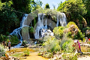 group of people are standing in the water beside a waterfall