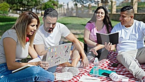 Group of people students sitting on grass studying at park