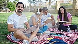 Group of people students sitting on grass studying at park