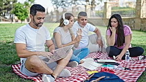 Group of people students sitting on grass studying at park