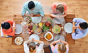 Group of people at table praying before meal