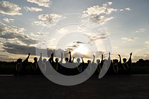 A group of people with their hands up at sunset.