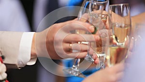 Group of people toasting at a celebration clinking their glasses together in congratulations , close up view of their