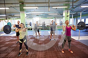 Group of people training with barbells in gym