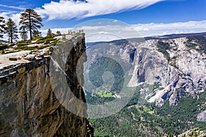 A group of people visiting Taft Point, a popular vista point; El Capitan, Yosemite Valley and Merced River visible on the right;