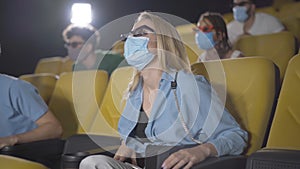 Group of people watching 3d film during Covid-19 pandemic lockdown in movie theater. Group of multiethnic cinema