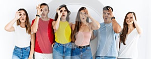 Group of people wearing casual clothes standing over isolated background doing ok gesture shocked with surprised face, eye looking