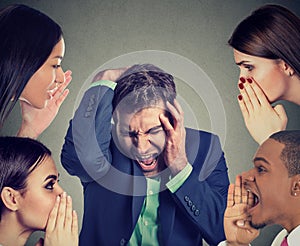 Group of people whispering to a desperate stressed business man photo