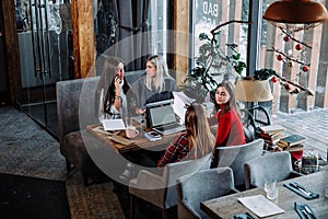 Group of people working on business project at cafe, sitting at table with sheets of paper and laptop