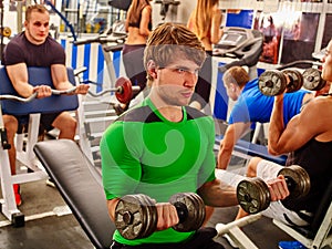 Group of people working with dumbbells at gym.