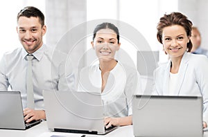 Group of people working with laptops in office