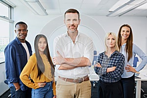 Group photo of diverse business people standing at office with male leader