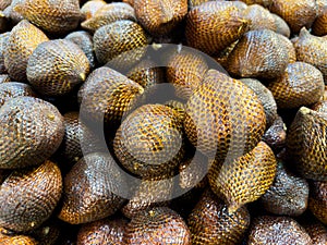 a group of a pile of lots of snake fruits, blackish brown color