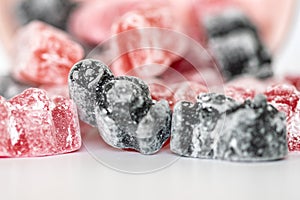 A group of pink and black jelly sweets with a dark sweet figure with a heart emblem on its front standing