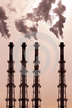 A group of pipes releases dark smoke steam vapor. environmental pollution, air pollution by toxic fumes