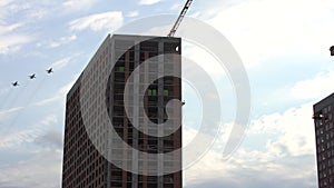 a group of planes flies in the cloudy sky above multi-storey apartment buildings. professional military pilots prepare