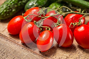 Group of plum Roma tomatoes ripe on a vine, on a wooden table