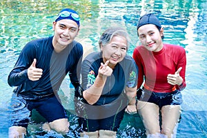 Group portrait of asian people of different ages smiling happily exercising in the water and doing hydrotherapy.