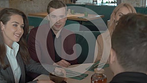 Group portrait of business colleagues talking while sitting at the table in cafe. Working partners discussing job and