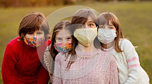 Group portrait of children in protective medical masks walking on street on sunset