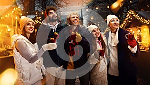 Group portrait of happy cheerful people, friends with cup of hot warming mulled-wine and enjoying moment before New Year