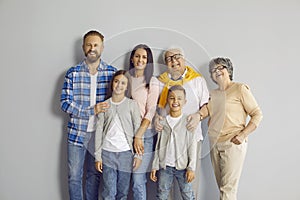 Group portrait of a happy family standing all together by a grey wall in the studio