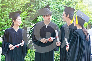 Group of Portrait happy students in graduation gowns holding diplomas on university campus