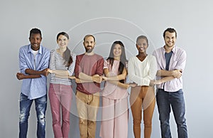Group portrait of happy young diverse friends standing together, holding hands and smiling