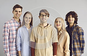 Group portrait of happy young people in casual clothes looking at camera and smiling