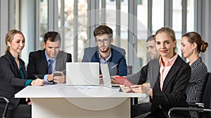 Group portrait of six business people team sitting and talking in conference together in an office and while the woman boss sit on