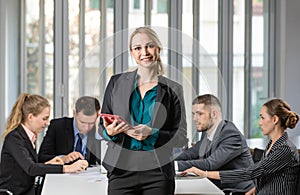 Group portrait of six business people team sitting and talking in conference together in an office and while the woman boss stand