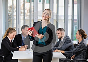 Group portrait of six business people team sitting and talking in conference together in an office and while the woman boss stand